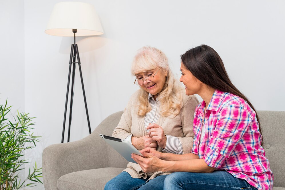 silly-senior-mother-her-daughter-using-digital-tablet-while-sitting-sofa_23-2148041378